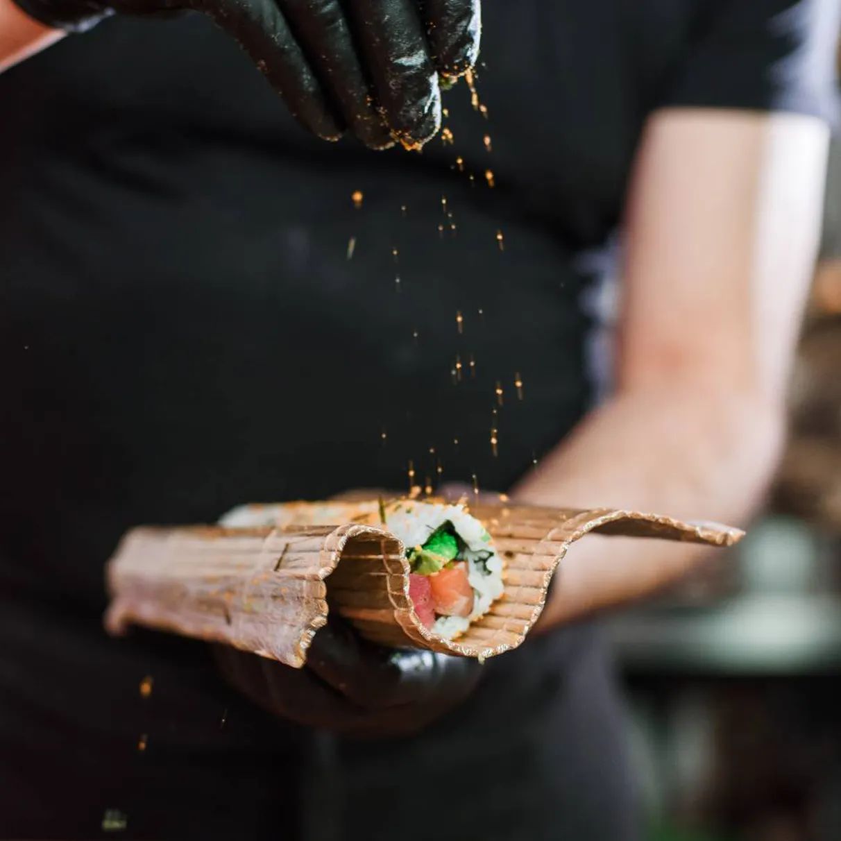 Sushi chef rolling a maki roll on a bamboo mat